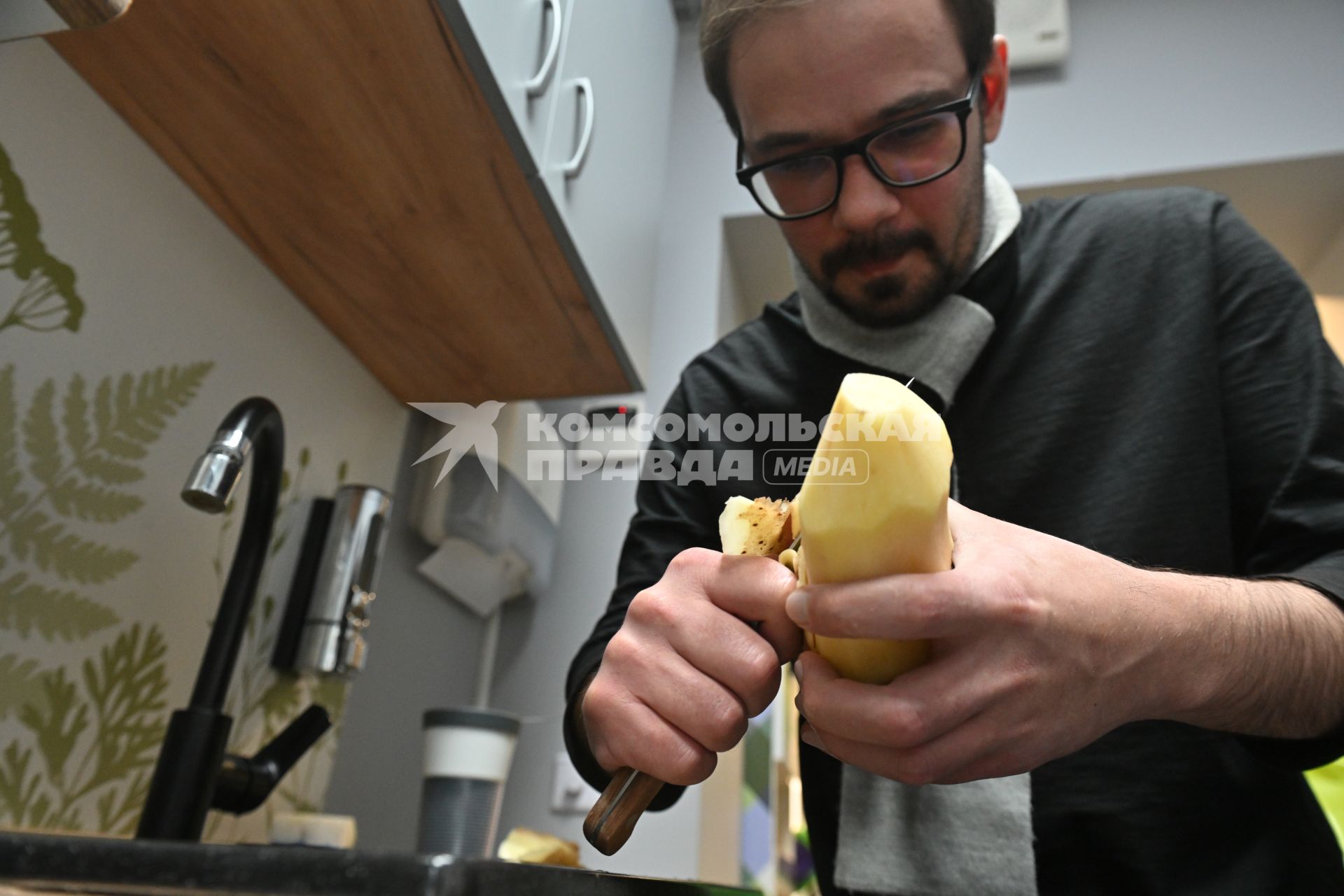 Мужчина чистит картошку